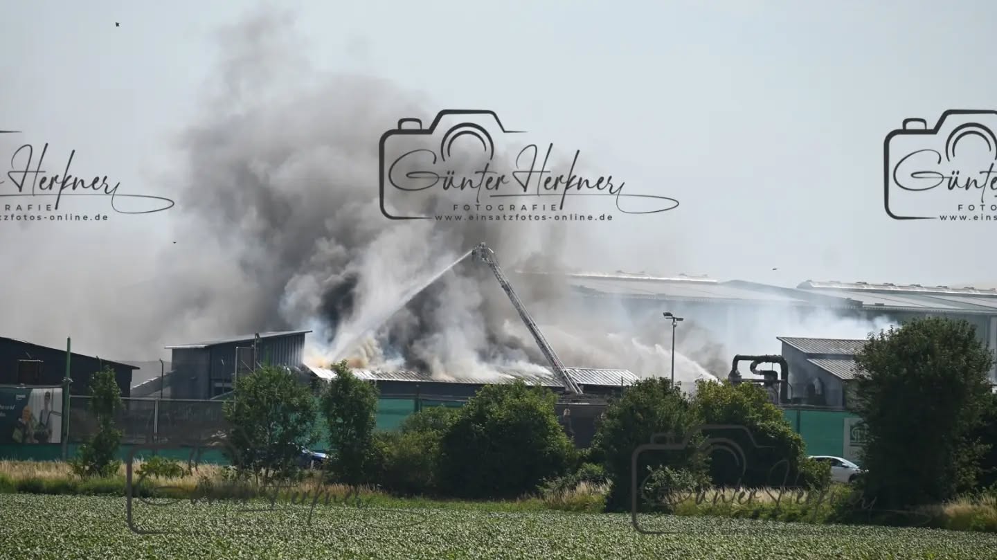 Lagerhalle von Recyclingbetrieb Wurzer brennt: Großaufgebot im Einsatz
🗓️Datum: 28.06.2026
⏰Uhrzeit: 10:21 Uhr
🚒🚑 Einsatzart: B 4
📍Einsatzort: Eitting
🚒🚑🚁🚓 Eingesetzte Kräfte:
Eine Lagerhalle ist in Brand geraten. Mehrere Feuerwehren bekämpfen den Brand mit starker Rauchentwicklung seit Stunden. Eine Warnmeldung an die Eittinger Bevölkerung ging raus.
Eitting – Eine Lagerhalle des Recyclingbetriebs Wurzer in Eitting ist am Sonntagvormittag gegen 10.20 Uhr in Brand geraten. Einsatzkräfte mehrerer Feuerwehren sind mit einem Großaufgebot vor Ort und bekämpfen das Feuer. Es kommt derzeit zu starker Rauchentwicklung.
Laut einem Sprecher des Polizeipräsidiums Oberbayern-Nord war am Sonntagvormittag gegen 10.20 Uhr Müll in einer Lagerhalle in Brand geraten, „und im Folgenden wohl auch die Lagerhalle selbst“. Über die Größe der Halle sowie Ausmaß des Schadens könne er noch keine Auskünfte geben. Verletzte habe es durch den Brand nicht gegeben. Aber aufgrund der sehr starken Rauchentwicklung in Richtung Osten „haben wir gerade vor ein paar Minuten auch noch über unsere Social Media Accounts Warnungen für die Bevölkerung in Eitting ausgesteuert“, sagte der Sprecher am Sonntag gegen 14.30 Uhr. „Sicherheit geht einfach vor. Man weiß ja nicht, was da genau in Brand geraten ist.“ Wegen der Brandursache werde noch ermittelt.
Wegen der Brandursache werde noch ermittelt. Dem Vernehmen nach soll eine Halle einsturzgefährdet gewesen sein und das Feuer auf ein weiteres Gebäude übergegriffen haben. Ein Sprecher der Firma Wurzer war am Sonntag nicht erreichbar.
Für die Feuerwehren war der Einsatz angesichts der ohnehin hohen Temperaturen eine ganz besondere Herausforderung. So war zu hören, dass die enorme körperliche Belastung für mehrere Einsatzkräfte zu viel wurde. Sie mussten selbst behandelt werden.
Bei Temperaturen um die 40 Grad kamen die vielen Atemschutzgeräteträger an ihr Limit: Mit rund 25 Kilogramm schweren Pressluftflaschen und in voller Montur gaben sie alles, um das Feuer schnellstmöglich unter Kontrolle zu bringen, sagt Sebastian Brendel, Pressesprecher der Kreisbrandinspektion Freising.
Quelle: Merkur online
📷 Günter Herkner